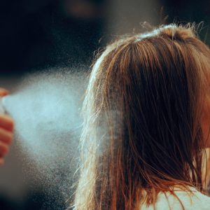 o imagine cu o sticlă de spray pentru volumul părului și o femeie cu părul plin de volum